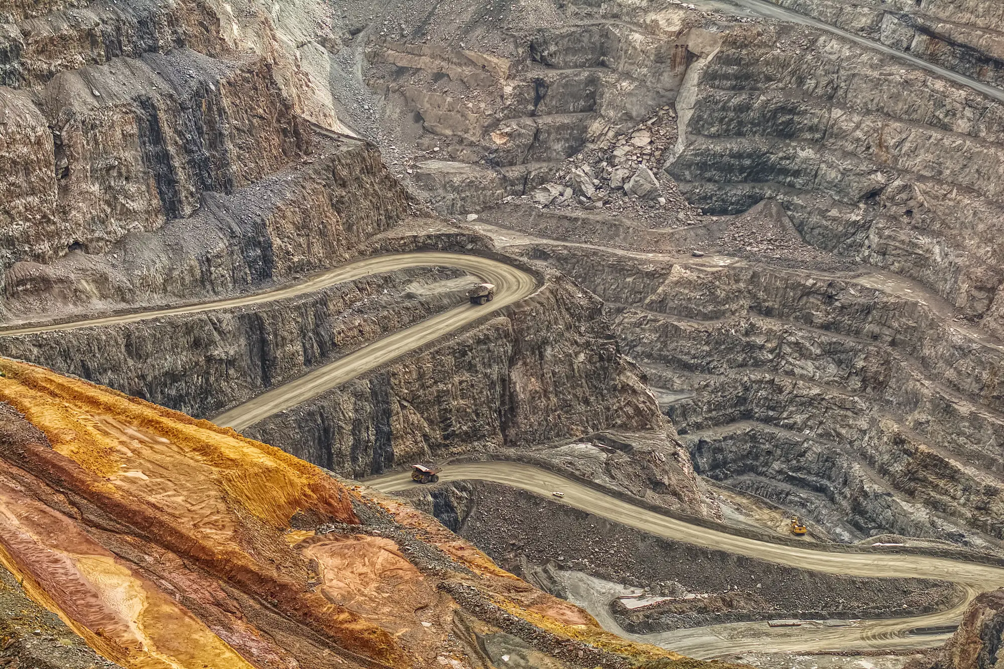 Benches and haul roads cut into the wall of a deep open pit
